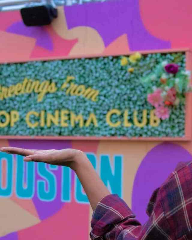 Alexiss Tyler - a black woman blogger standing in front of sign that read "Rooftop Cinema Club" in Uptown Houston Texas